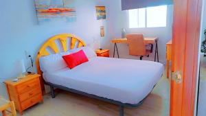 une chambre avec un lit avec un oreiller rouge dessus dans l'établissement Apartamento reformado con terraza vistas al mar y a las piscinas de Magic World garaje y piscina frente a Balneario Aire acondicionadowifi, à Oropesa del Mar