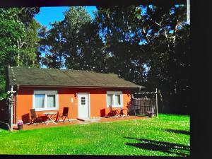 una piccola casa arancione con un tavolo e delle sedie in un campo di Kölp - Gentz H a Kölpinsee auf Usedom