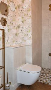 a bathroom with a toilet and flowers on the wall at VacationClub - Baltic Waves Resort Apartament A325 in Międzywodzie