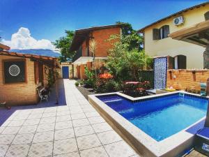 a swimming pool in a yard next to a house at Portal Suítes Casa do Lago in Paraty