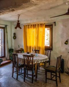 a dining room table with chairs and a yellow curtain at Trullo of the Living Garden in Ostuni