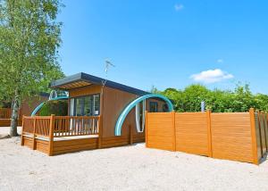 a small house with a playground behind a fence at Wild Rose Holiday Park in Colby