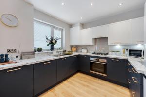 a kitchen with white cabinets and a clock on the wall at Watford Lodge - Air Host & Stay - A Home in the Heart of Anfield in Liverpool