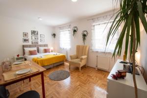 a bedroom with a bed and a chair and a table at Studio Sunlight+ private parking in Novi Sad
