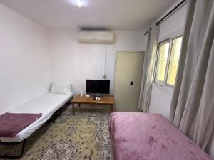 a room with two beds and a desk with a television at Desert Rose Villa 7 in Abu Dhabi
