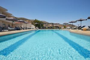 a large swimming pool with chairs and umbrellas at Mila Malia Suites in Malia