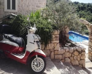 un scooter automobile garé à côté d'un mur en pierre dans l'établissement Villa Toni, à Tučepi