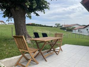 a wooden table and chairs next to a tree at Etxe ttikia in Ahetze