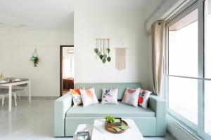 a living room with a blue couch with pillows at Trendy 2bhk Apartment near BKC in Mumbai +24 photos