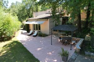 カルパントラにあるDomaine en Provence Gîte la Ferrandiereの傘とテーブルと椅子のあるパティオ