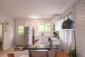 Il comprend une cuisine équipée d'un réfrigérateur et d'une table avec des chaises. dans l'établissement Tropical Haven - 2BR Hilo, à Hilo