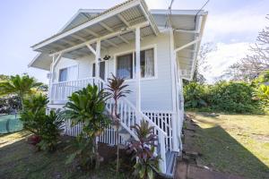 une petite maison blanche avec une balustrade blanche dans l'établissement Tropical Haven - 2BR Hilo, à Hilo