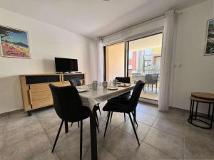 una sala da pranzo con tavolo, sedie e televisione di Appartement 3 pièces climatisé avec parking - Saint-Cyr-sur-Mer - FR-1-845-3 a Saint-Cyr-sur-Mer