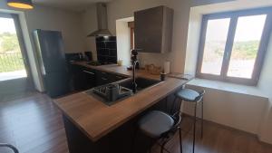 a kitchen with a sink and a counter with stools at la maison de pejusclat in Villesèque