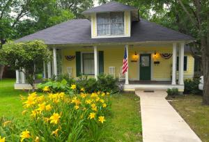 a yellow house with a flag in the yard at Brooks House Suites in Mineola