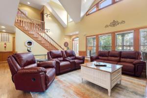 Il comprend un salon doté d'un mobilier en cuir brun et d'un escalier. dans l'établissement 40-Love, à Corolla