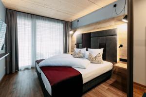 una camera da letto con un letto grande con lenzuola e cuscini bianchi di Hotel Gasthof Zum Schwanen a Reutte