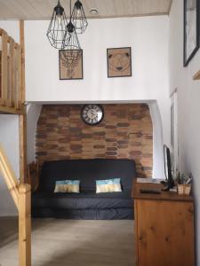 a living room with a couch and a clock on a wall at CAUTERETS Appart centre ville et calme idéal pr rando, ski et cure in Cauterets