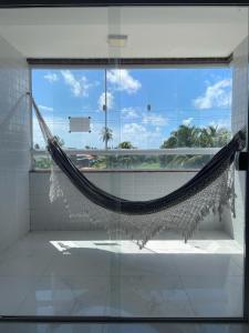 a hammock in a room with a large window at Apartamento 100m da praia in Conde