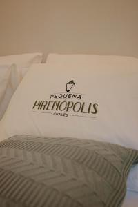 a bed with a comforter with a sign on it at Pequena Pirenópolis Chalés in Pirenópolis