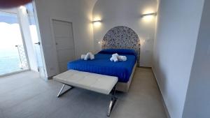 Un dormitorio con una cama azul y un banco. en La Culla sul Mare centro storico, en Amalfi