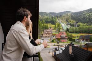 a man holding a camera looking out of a window at Wielka Krokiew Residence&SPA - Zakopane - JACUZZI, SAUNA, TĘŻNIA SOLANKOWA, SPA, GRILL in Zakopane