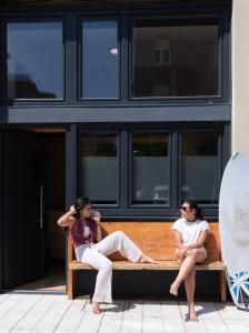 two women sitting on a bench in front of a building at Suances Surf Beach in Suances
