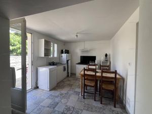 a kitchen with a table and chairs and a refrigerator at Chaleureuse maisonnette au cœur de Ruoms avec terrasse et parking - FR-1-697-35 in Ruoms