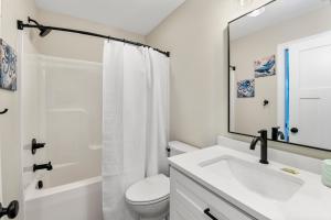 a bathroom with a sink and a toilet and a mirror at Masons Beach House Getaway in Kill Devil Hills +23 photos