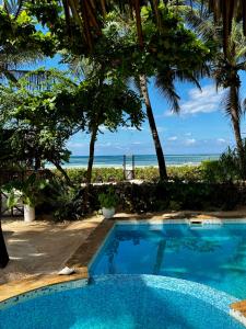 a swimming pool with the beach in the background at Villa Kipara - Sea front with Private Pool & Jacuzzi in Pwani Mchangani