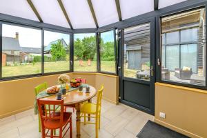 a conservatory with a table and chairs and windows at La Richaumoise - Maison avec grand jardin in Sains-Richaumont
