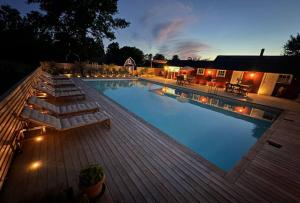 a large swimming pool with a wooden deck at night at Ljusterö Logi in Norra Ljustero