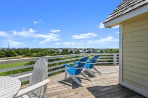 three chairs and a table on a deck with a view at Milky Way in Nags Head