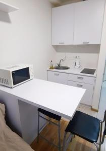 a white kitchen with a microwave and a table at Smart House on Mashynobudivna in Kyiv