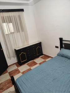 a bedroom with a bed and a dresser and a window at Lovely and comfortable apartment in Martil in Martil