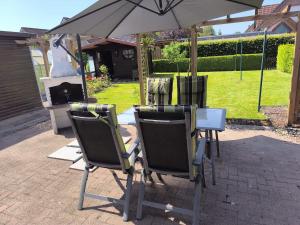 a group of chairs and an umbrella next to a fireplace at Ferienhaus Dini, 25668 in Weener
