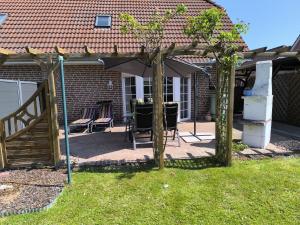 una pérgola con sillas y una mesa en un patio en Ferienhaus Dini, 25668, en Weener