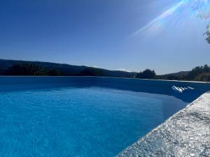 a pool of blue water with mountains in the background at Pensão Repouso do Peregrino in Paredes de Coura