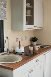 a kitchen counter with a sink and white cabinets at Ribble Valley Retreat in Langho