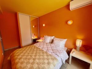 滨海卡瓦莱尔Appartement rénové 1 chambre à Cavalaire, proche plage, climatisé avec parking - FR-1-226B-107的卧室里有一张床，墙壁是橙色的