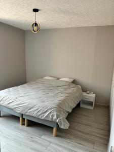 a white bedroom with a bed and a night stand at Au cœur de la Meuse in Damvillers