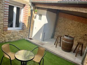 a patio with a table and chairs and a barrel at Au cœur de la Meuse in Damvillers