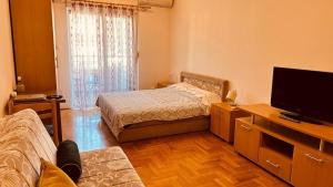 a bedroom with a bed and a tv and a couch at Budva Summer House in Budva
