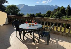 une table avec des verres à vin et des chaises sur une terrasse dans l'établissement Casa Corsini, à Porto Valtravaglia