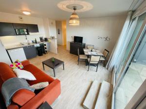 ein Wohnzimmer mit einem orangenen Sofa und einer Küche in der Unterkunft Terrasse & Confort à Rouen - 396 in Rouen