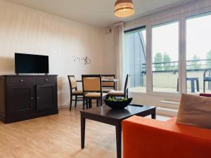 ein Wohnzimmer mit einer Couch und einem Tisch mit einem Fernseher in der Unterkunft Terrasse & Confort à Rouen - 396 in Rouen