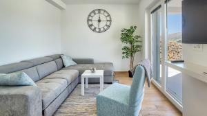 ein Wohnzimmer mit einer Couch und einer Uhr an der Wand in der Unterkunft Vila Romana by Resort Čulina in Metajna