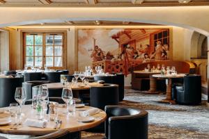 a restaurant with tables and chairs and a painting on the wall at Les Chalets du Mont d'Arbois & Spa, Megève in Megève