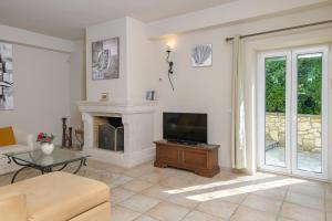 a living room with a television and a fireplace at Villa Moyria by PosarelliVillas in Kassiopi