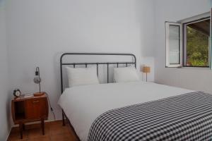 a bedroom with a large white bed and a window at Casas Porta Alegre in Portalegre